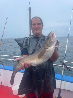 a man holding a fish on a boat in a body of water