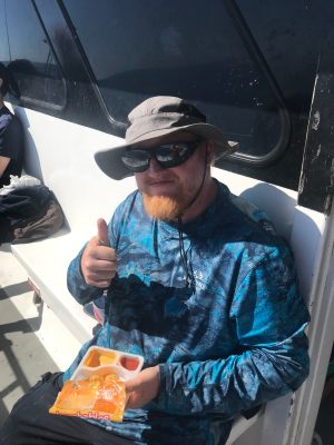 a man wearing a hat and sunglasses sitting on a boat