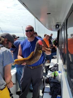 a group of people standing next to a man holding a fish