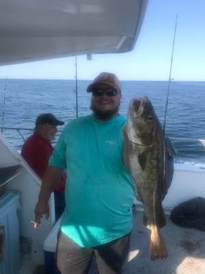 a man and a woman standing in front of a fish on a boat